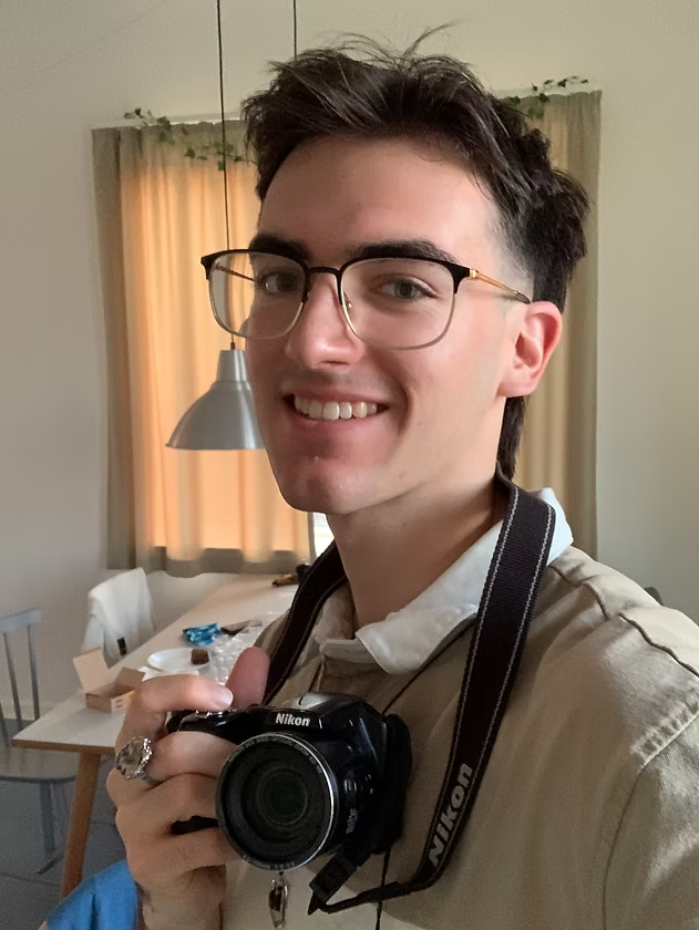 Jayson Kunkel smiling and holding a digital camera